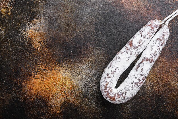 Spanish salami fuet wurst on dark background, top view with copy space.