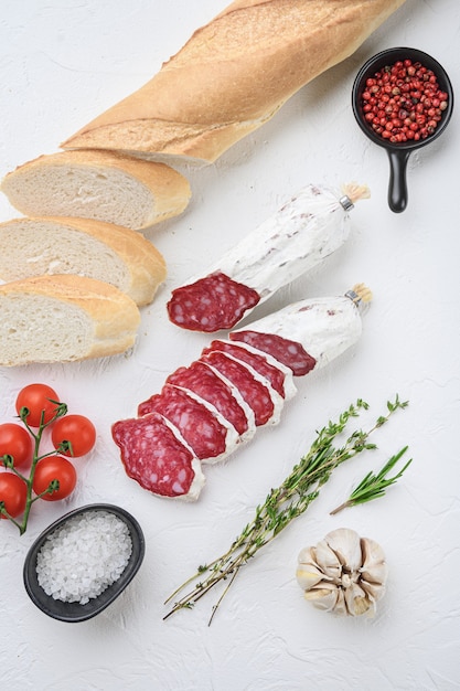 Spanish salcichon slices with panini and herbs on white surface