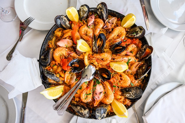 Foto piatto di riso alla paella di pesce spagnolo con gamberi freschi, scampi, cozze, calamari, polpi e capesante servito in padella. vista dall'alto. ristorante