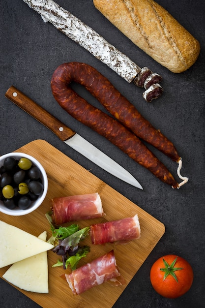 Spanish serrano ham, cheese and sausage on black surface