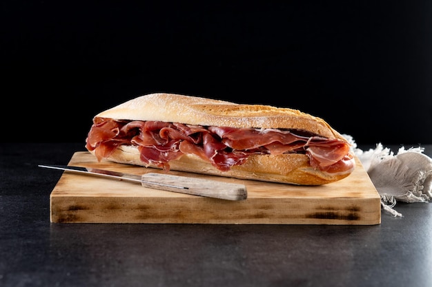 Foto sandwich di prosciutto serrano spagnolo su sfondo nero ardesia