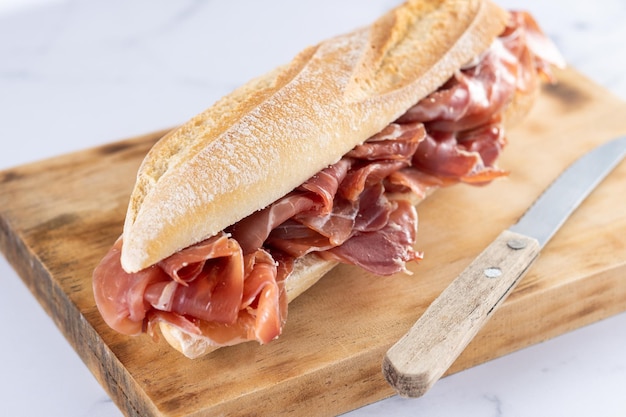 Spanish serrano ham sandwich on white marble background