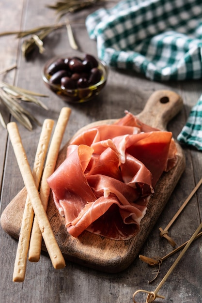 Spanish serrano ham with olives and breadstick