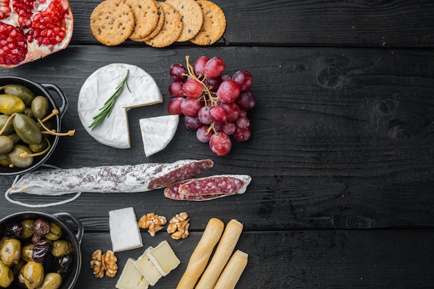 Spanish snacks, meat cheese, herbs set, on black wooden table, top view 