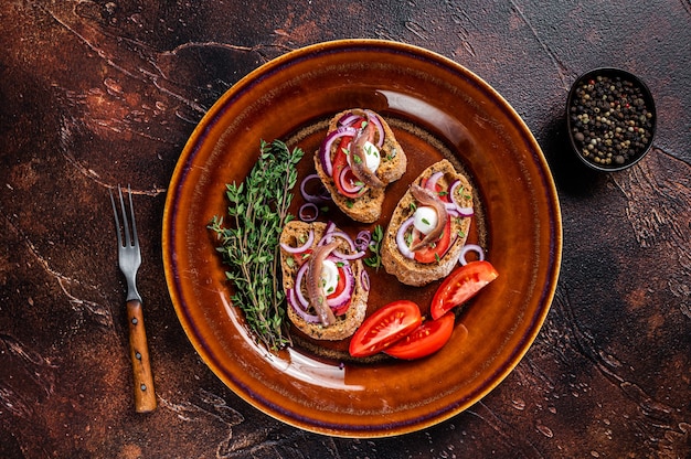 Spanish tapas on bread with olive oil, herbs, tomatoes and spicy anchovy fillets