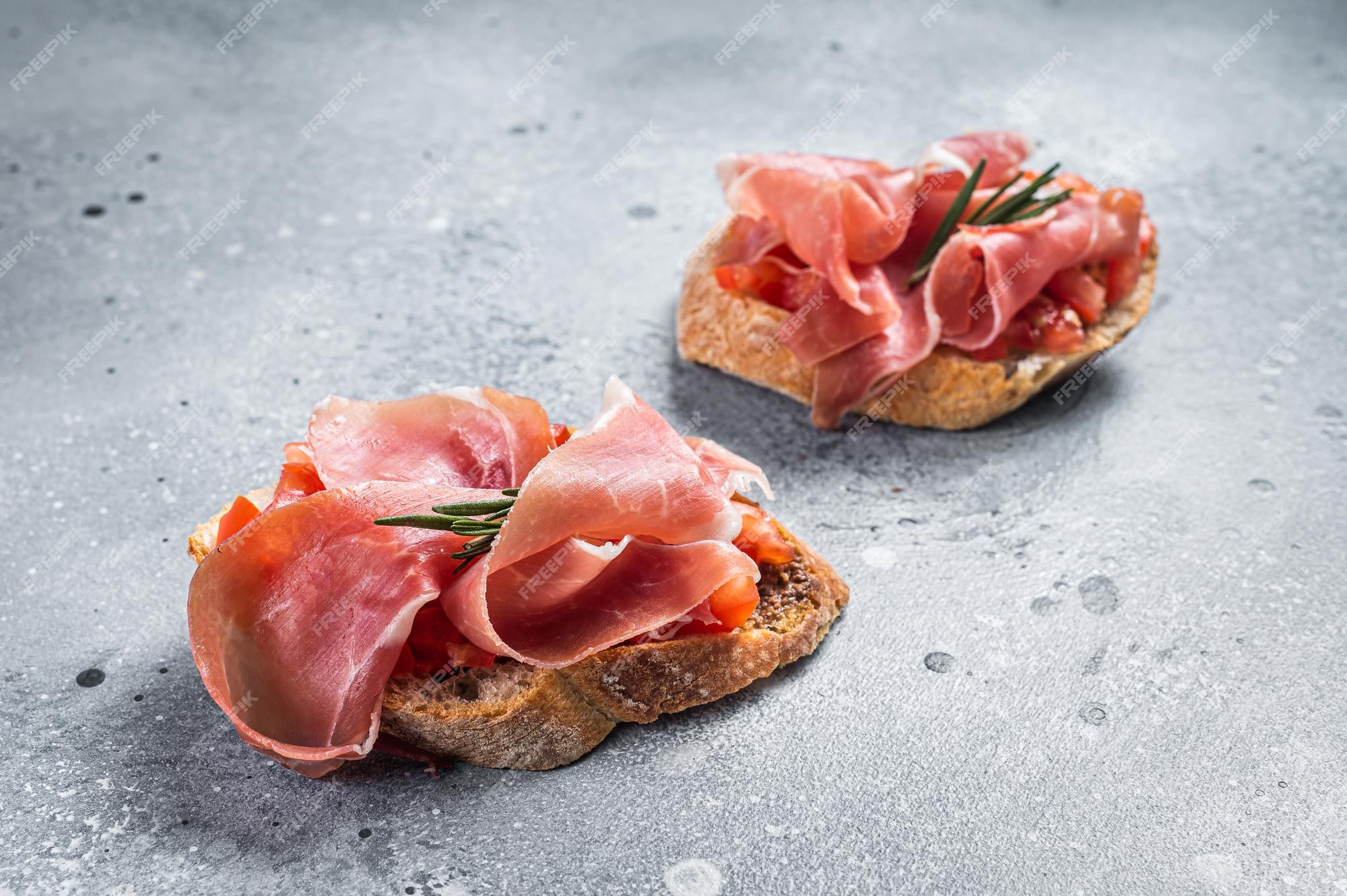 Premium Photo | Spanish tapas with tomatoes and cured slices of jamon  iberico ham, fresh toasts. gray background. top view.