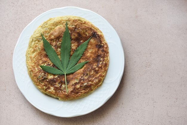 Spanish tortilla plate with CBD leaf, food concept with therapeutic properties.