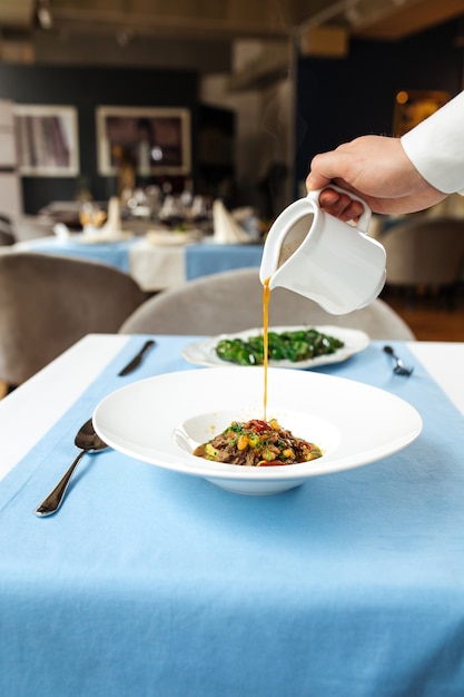 Spanish traditional oxtail soup in white plate on the blue table