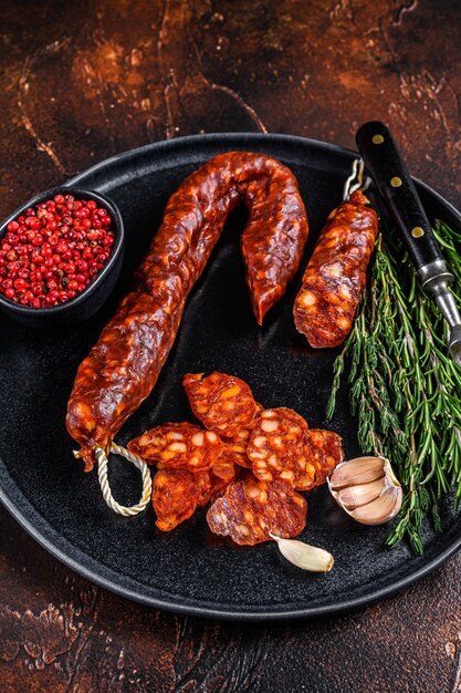 Spanish traditional tapas Sliced chorizo pork dry cured sausage. Dark background. Top view.