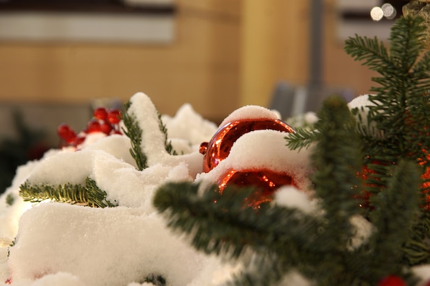 Spar takken en rode ornamenten voor kerst buiten bedekt met sneeuw.