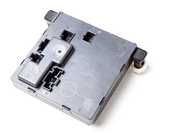 A spare part for a car engine control unit in black on a white isolated background is a connecting center of subsystems components and assemblies Electronic ignition unit