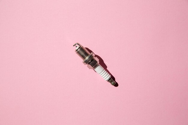 Spark plug car candle lies against a pink background auto engine electrician flat lay opy space