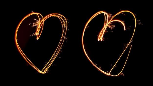 Photo sparkler light painted in shape as two hearts at night time