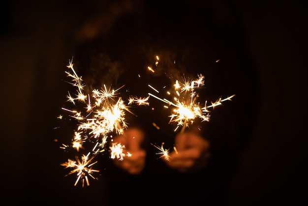 Sparklers are burning on a dark background, the concept of the holiday, Christmas and New Year 2022