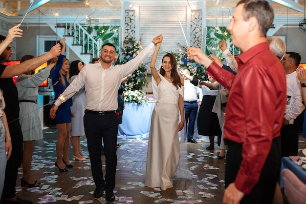 Sparklers at the wedding of the newlyweds in the hands of joyful guests