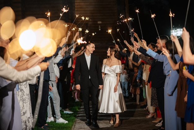 Sparklers at the wedding of the newlyweds in the hands of joyful guests