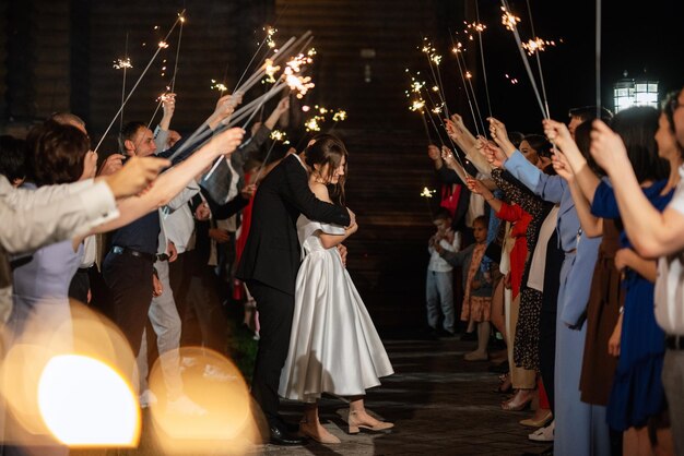 Sparklers at the wedding of the newlyweds in the hands of joyful guests