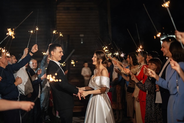 Sparklers at the wedding of the newlyweds in the hands of joyful guests