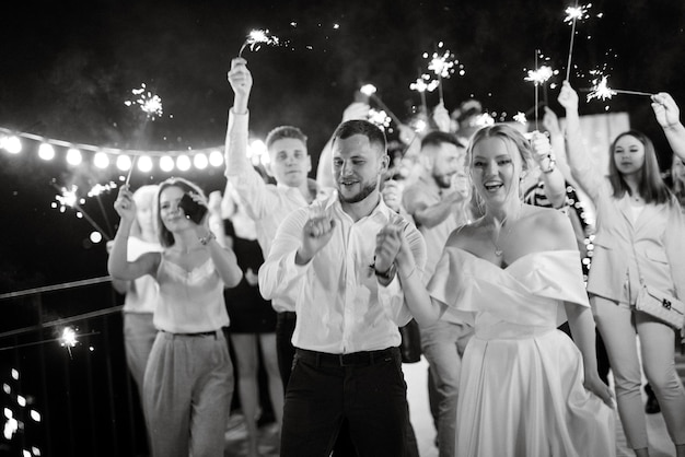 Sparklers at the wedding of the newlyweds in the hands of joyful guests