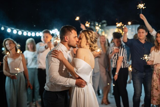 Sparklers at the wedding of the newlyweds in the hands of joyful guests