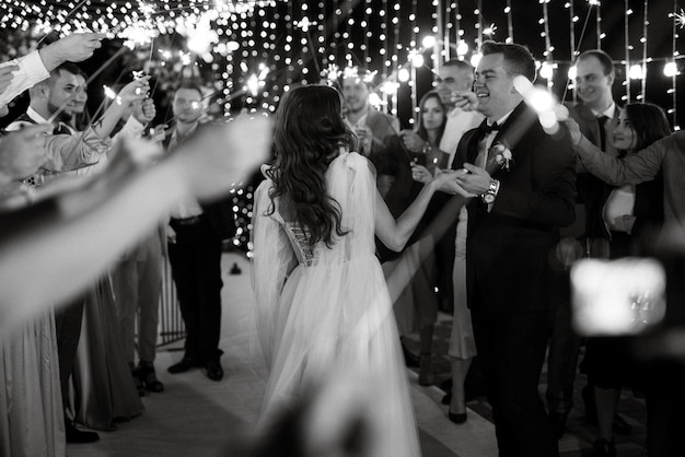 Photo sparklers at the wedding of the newlyweds in the hands of joyful guests