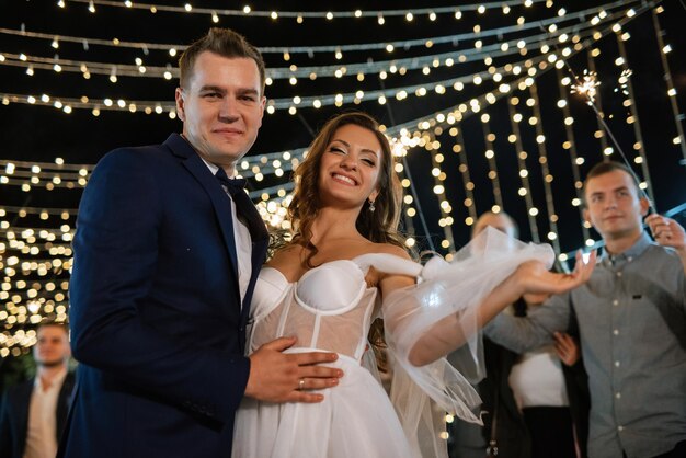 Sparklers at the wedding of the newlyweds in the hands of joyful guests