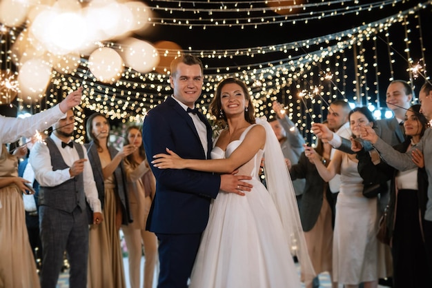 Sparklers at the wedding of the newlyweds in the hands of joyful guests