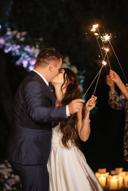 Sparklers at the wedding of the newlyweds in the hands of joyful guests