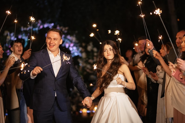 Sparklers at the wedding of the newlyweds in the hands of joyful guests