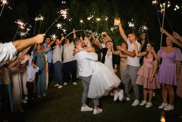 Sparklers at the wedding of the newlyweds in the hands of joyful guests