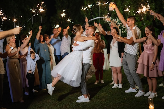 Sparklers at the wedding of the newlyweds in the hands of joyful guests