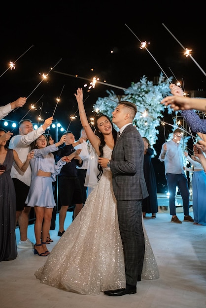 Sparklers at the wedding of the newlyweds in the hands of joyful guests