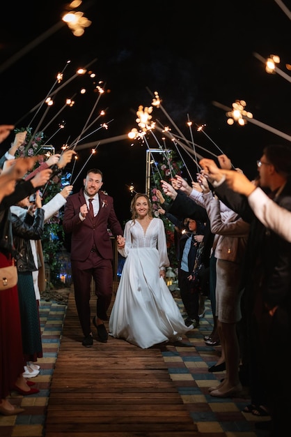 Sparklers at the wedding of the newlyweds in the hands of joyful guests