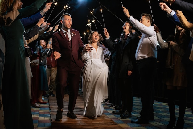 Sparklers at the wedding of the newlyweds in the hands of joyful guests