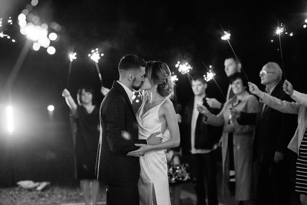 Sparklers at the wedding of the newlyweds in the hands of joyful guests