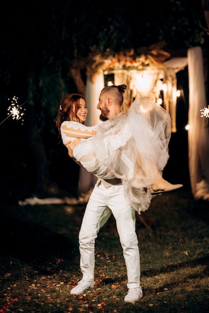 Sparklers at the wedding of the newlyweds in the hands of joyful guests