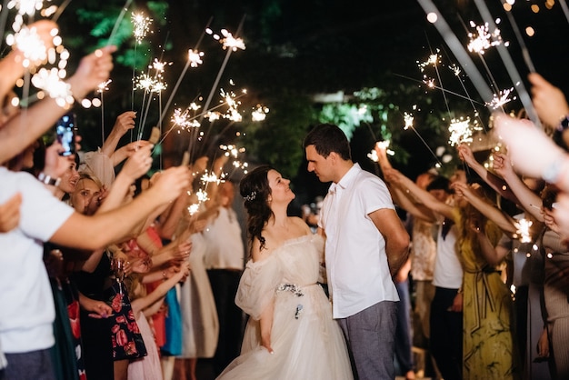 Sparklers at the wedding of the newlyweds in the hands of joyful guests