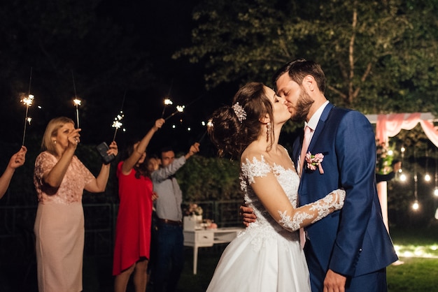 Sparklers at the wedding of the newlyweds in the hands of joyful guests