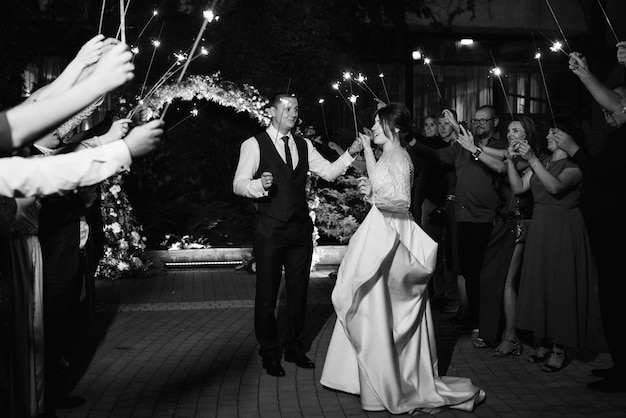 Sparklers at the wedding of the newlyweds in the hands of joyful guests