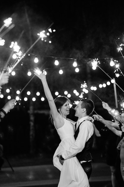 Sparklers at the wedding of the newlyweds in the hands of joyful guests