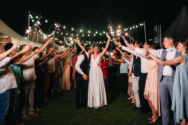 Sparklers at the wedding of the newlyweds in the hands of joyful guests