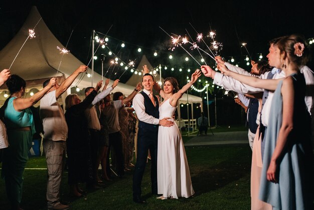 Sparklers at the wedding of the newlyweds in the hands of joyful guests