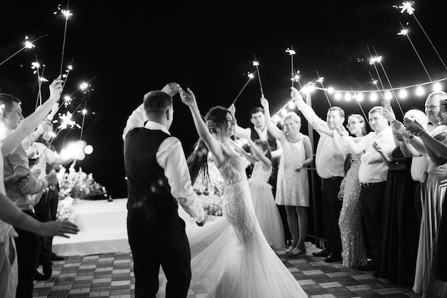 Sparklers at the wedding of the newlyweds in the hands of joyful guests