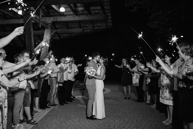 Sparklers at the wedding of the newlyweds in the hands of joyful guests