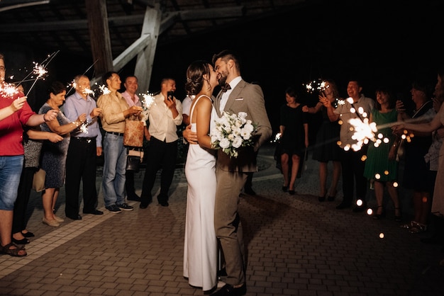 Sparklers at the wedding of the newlyweds in the hands of joyful guests