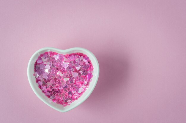 Sparkles in heart shaped bowl, ceramic cup on pink