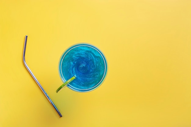 Photo a sparkling blue glitter drink decorated with lime stands on a yellow