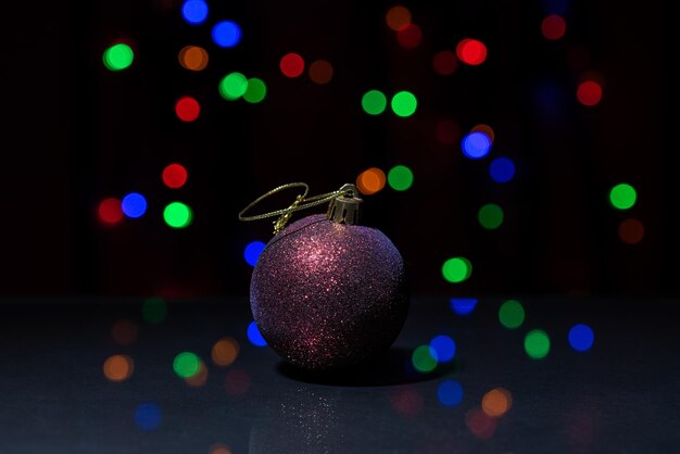 Sparkling bright Christmas ball on a glass table top with different bokeh