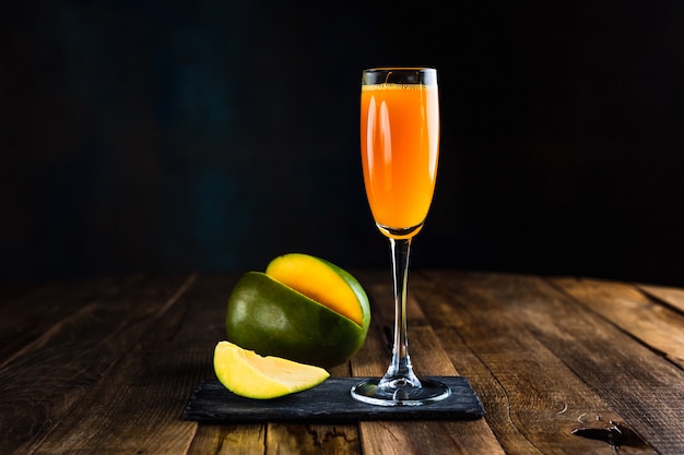 A sparkling cocktail with mango in a flute glass