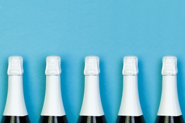 Bottiglia di spumante in fila su sfondo blu concetto di feste e celebrazioni